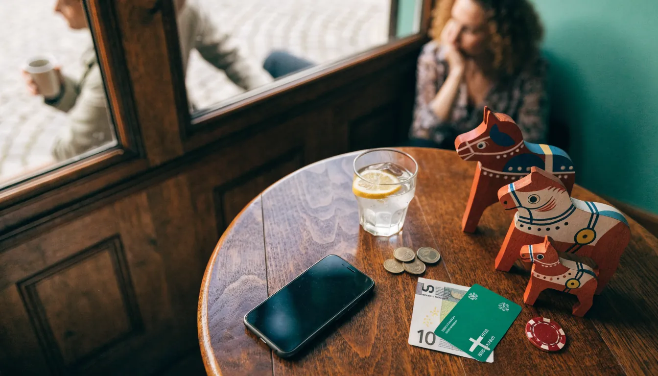 Euro-mynt, en svensk Dala-häst och casinokort på ett träbord